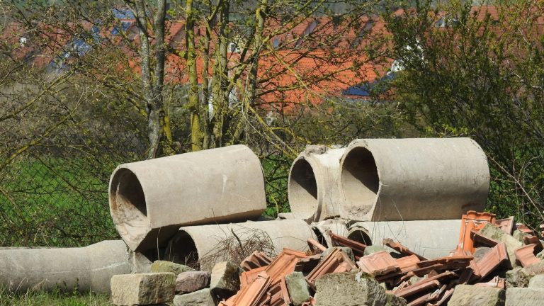 a pile of cement pipes sitting on top of a pile of rocks
