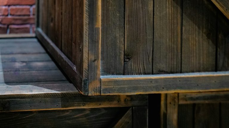 a close up of a wooden bench near a brick wall